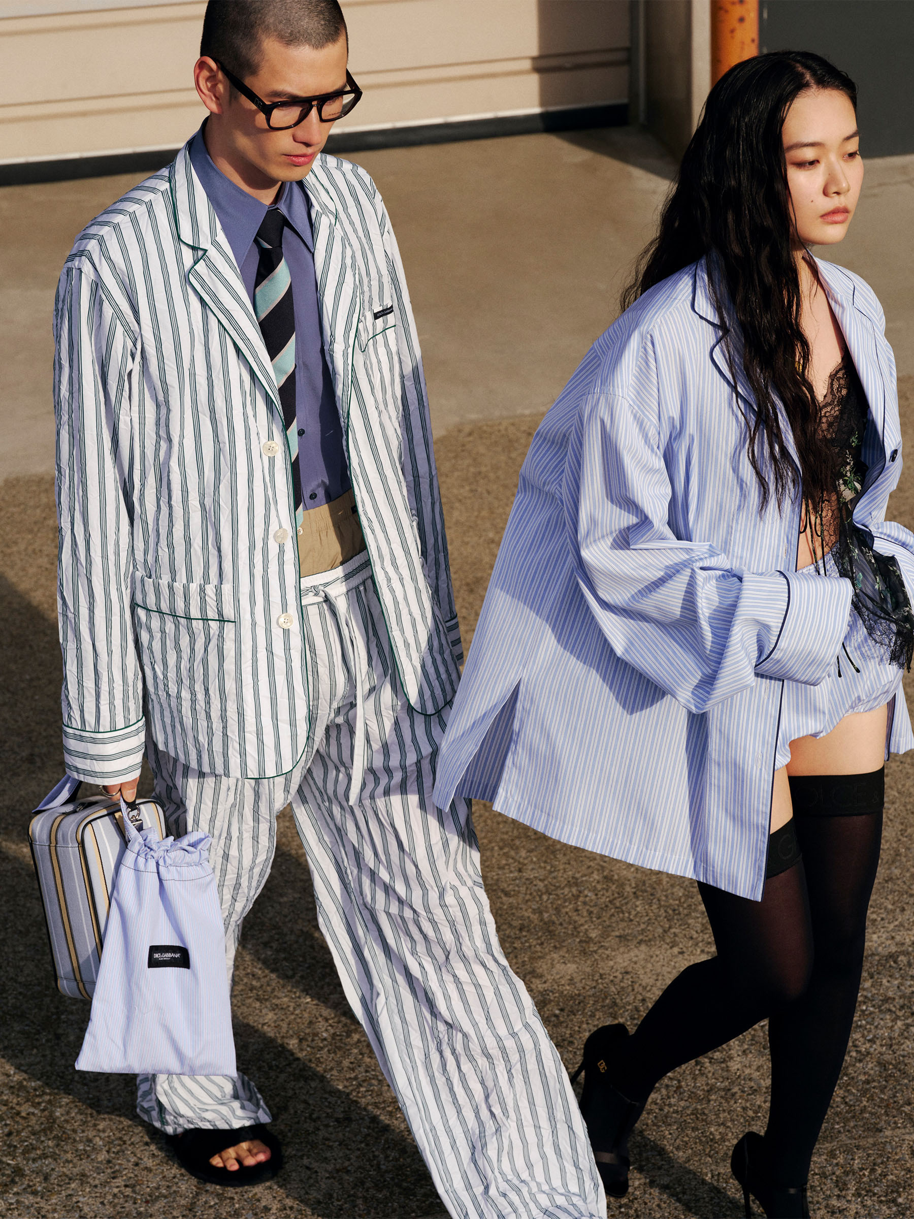 写真: [右]シャツ・トップス・パンツ・ブラ・ソックス・サンダルを着用する女性と[左]ジャケット・シャツ・パンツ・バッグ「ロック」・バッグ・サンダル・ネクタイ・メガネを着用する男性